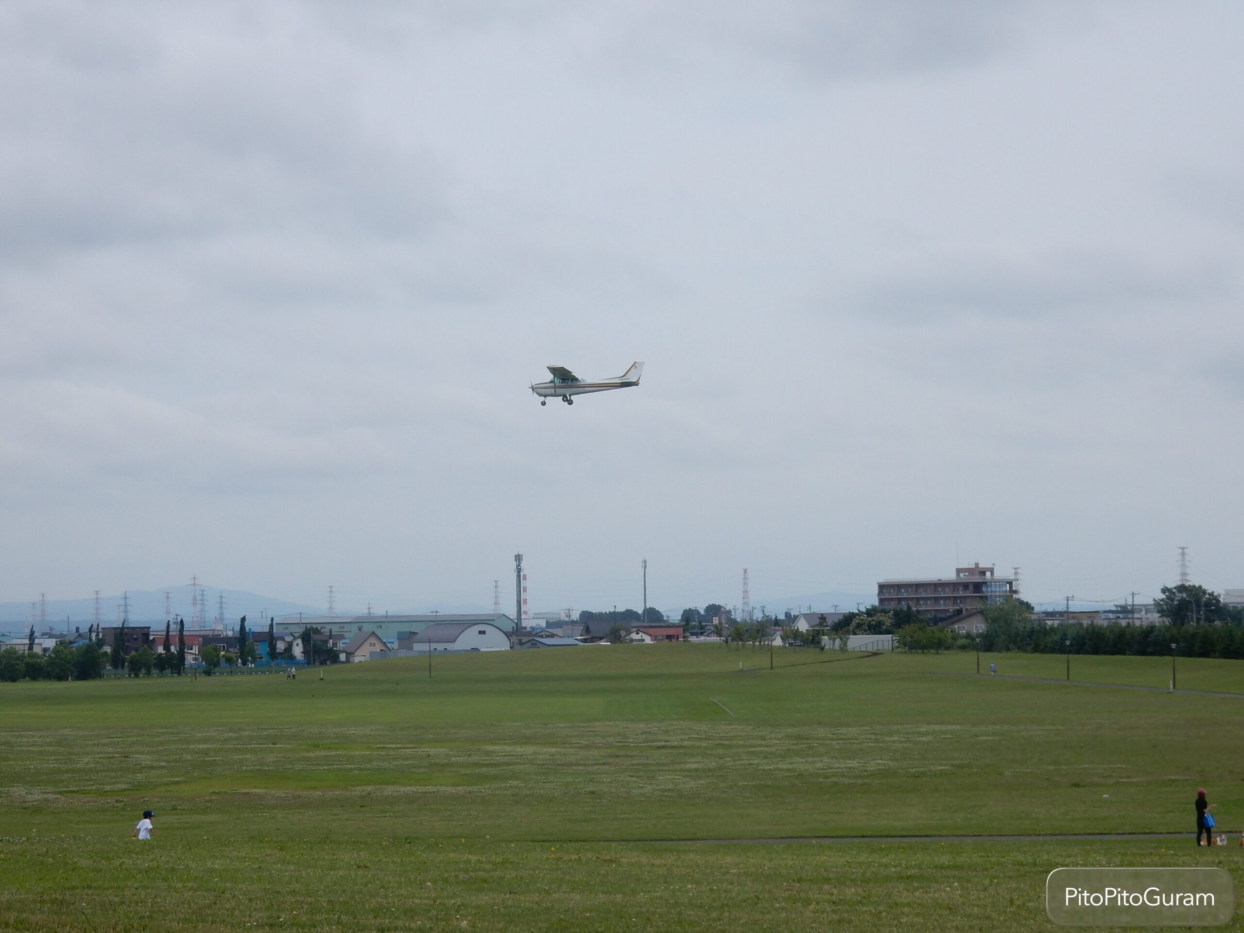 丘珠空港緑地でプロペラ機を見上げる広大な芝生と青空