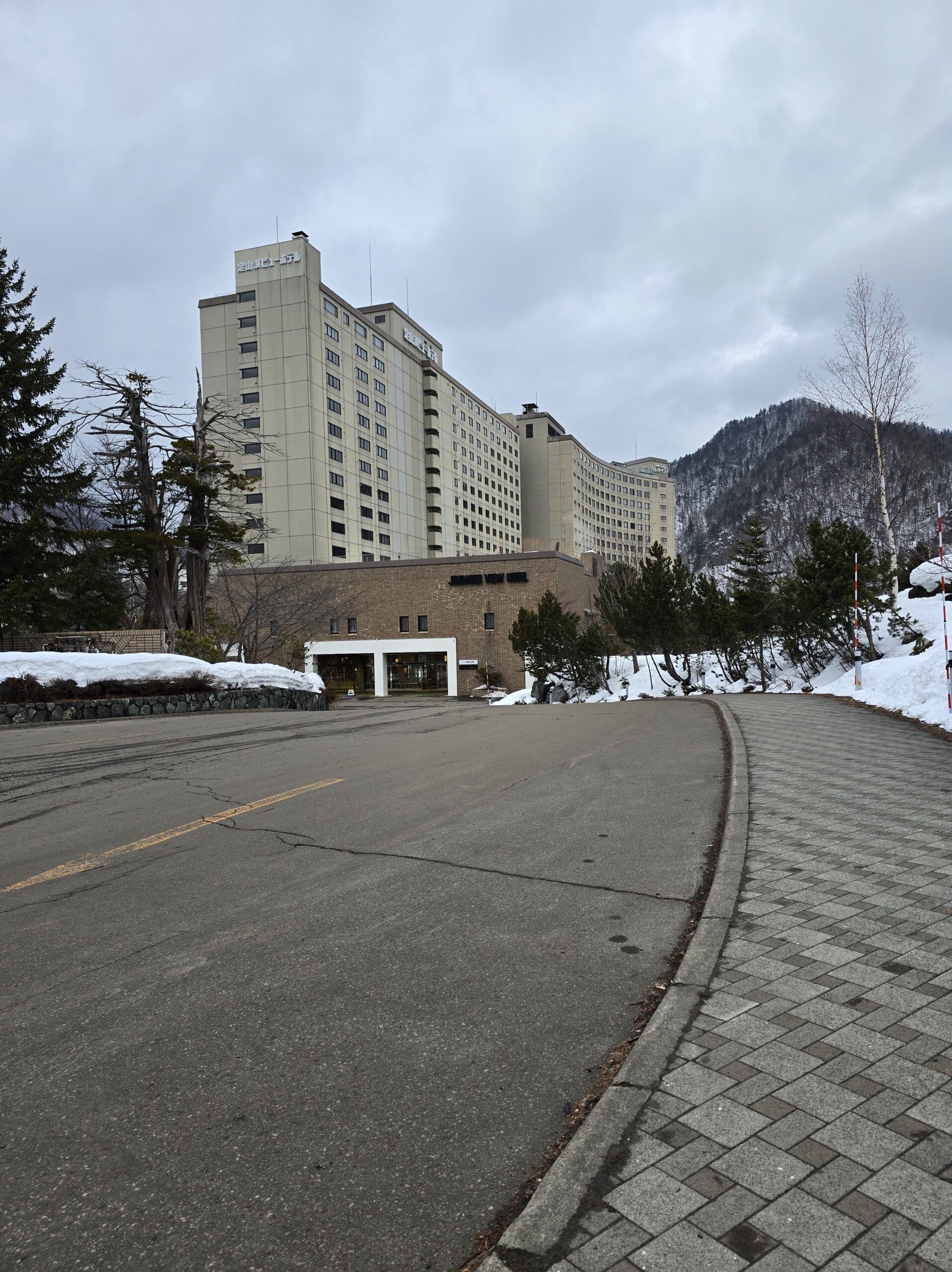 定山渓ビューホテルの外観。3月初旬、まだ雪が残る温泉街にそびえ立つ、北海道最大級のプール「ラグーン」を備えたホテル。