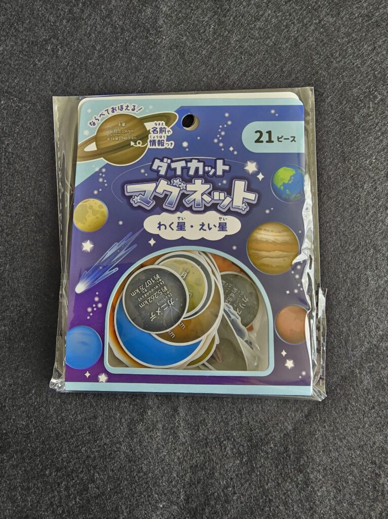 セリアで購入した「ダイカットマグネット わく星・えい星」のパッケージ写真。宇宙を背景に地球や土星のイラストが描かれている。