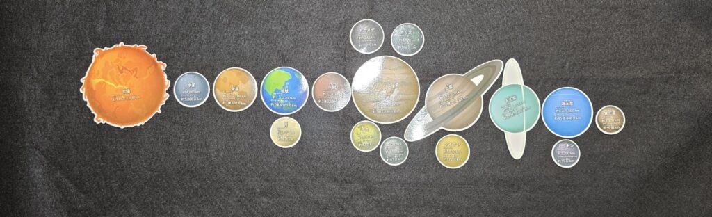 セリアで購入した「ダイカットマグネット わく星・えい星」のパッケージ写真。宇宙を背景に地球や土星のイラストが描かれている。